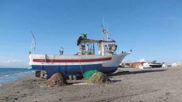 Grote en kleine boten staan geparkeerd op houten balken op het strand.